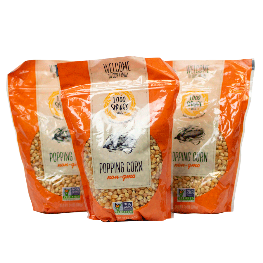 Three orange bags of Popping Corn with the 1000 Springs Mill logo on the front