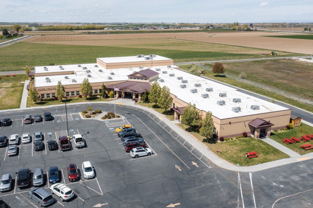 Aerial view of a school building with fields in the background