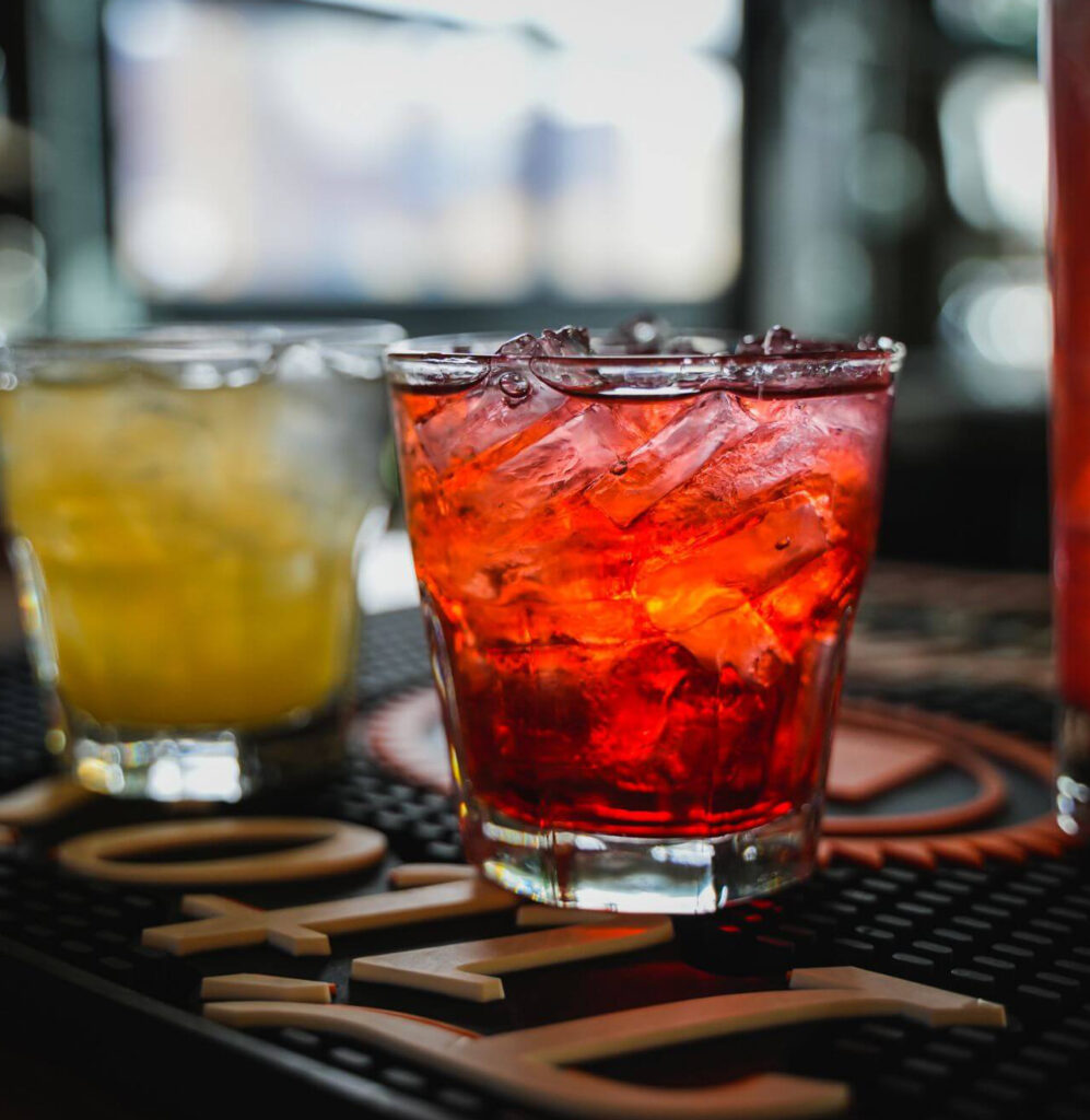 An image of two glasses with orange and red beverage inside.
